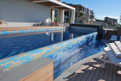 Modern residential swimming pool with tiled water feature and cascading waterfall