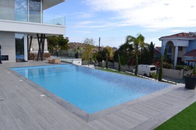 Modern residential swimming pool with luxury home and landscaped garden