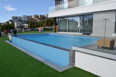 Modern residential swimming pool with tiled walls and landscaped garden