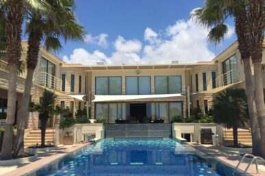 Luxury residential swimming pool with stone villa and palm trees